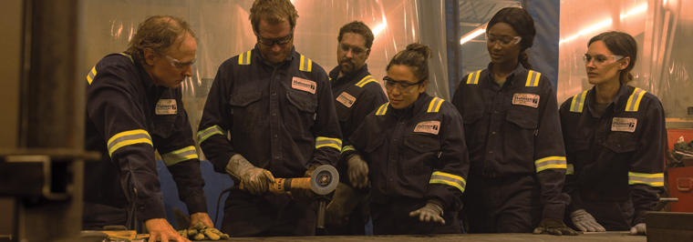 Group of six industrial employees wearing branded FR enhanced visibility uniforms